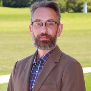Adam Rengstorf stands in front of a grassy field