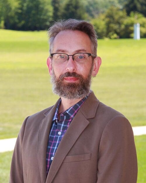 Adam Rengstorf stands in front of a grassy field
