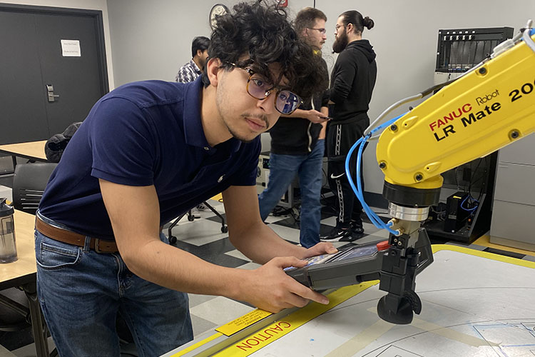 A PNW student works with a piece of mechanical equipment.