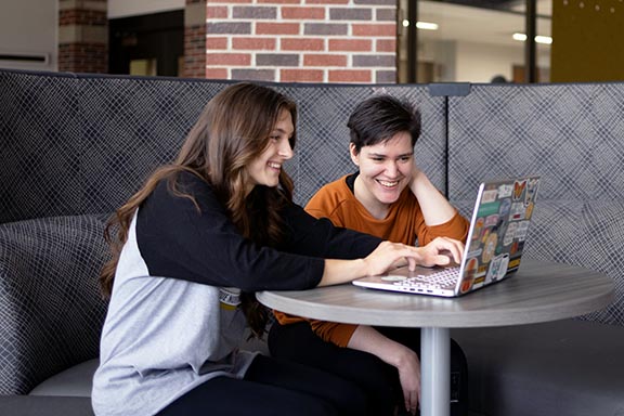 Students collaborate together over a laptop