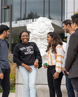5 students talking in a group in front of the NILS Building