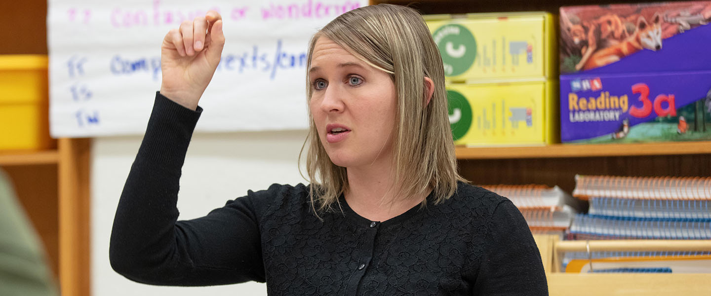 A PNW students sits in a classroom surrounded by education posters.