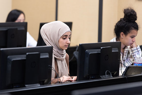 Two PNW students sit at a row of computers