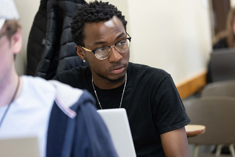 A student in a black shirt works on a laptop.