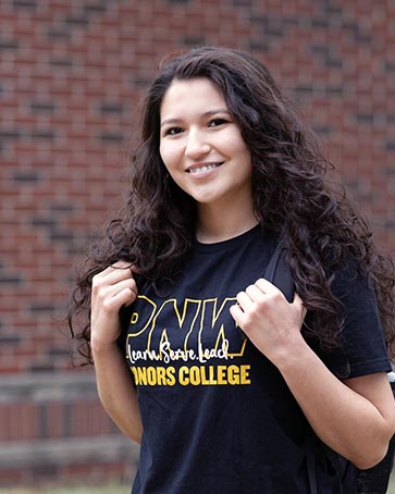 A student stands outdoors in a PNW Honors College t-shirt
