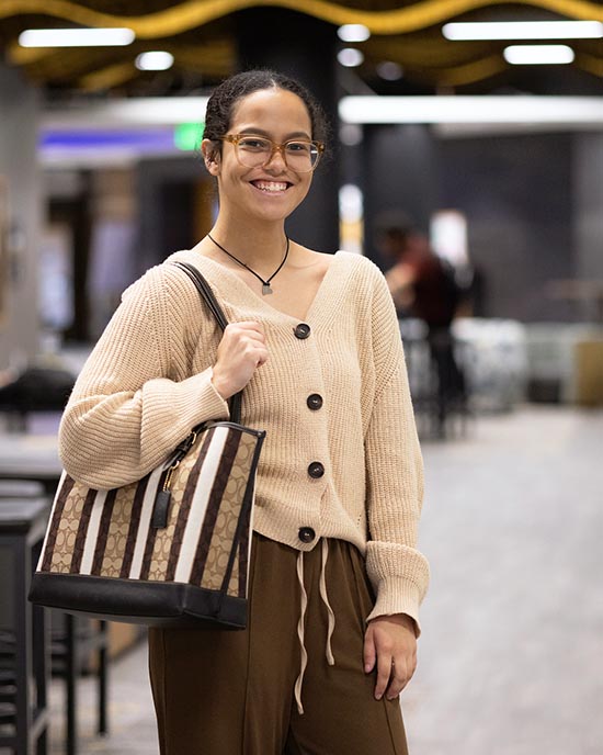 A PNW student stands with a striped purse in the Mane Zone