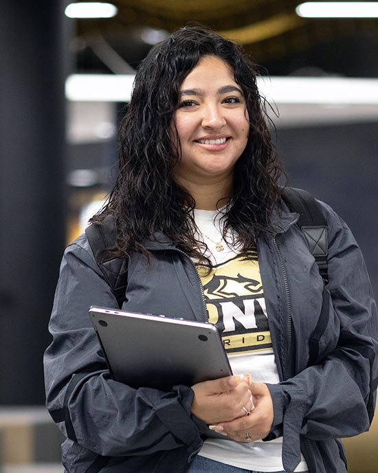 A PNW student holds books on campus