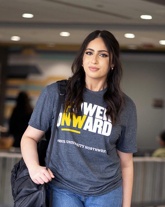 A PNW student stands on campus in a Power Onward t-shirt