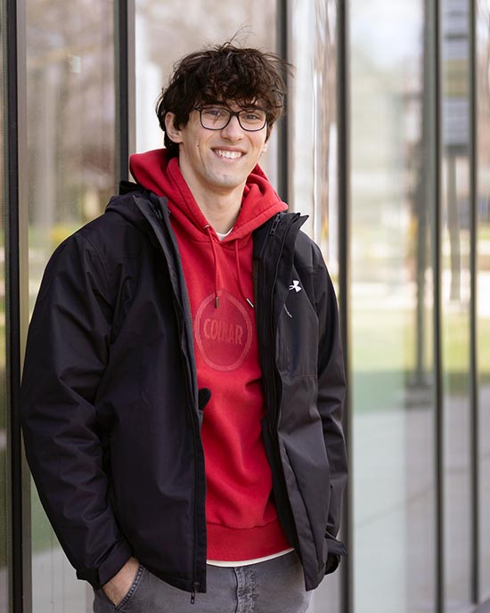 A PNW student stands outdoors in front of a building