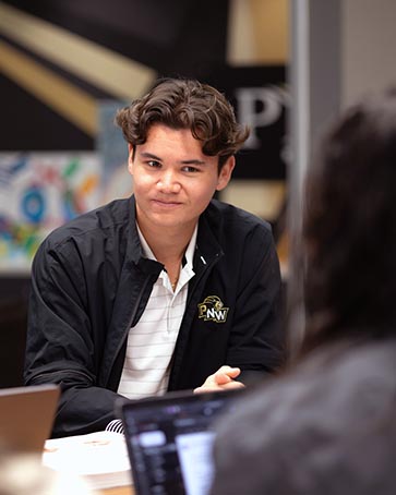 A PNW student listens at a conference table
