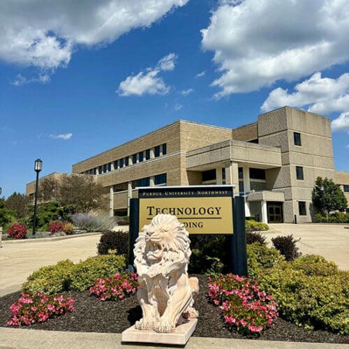 A lion statue on the PNW Westville Campus. The Technology Building sign is located behind the statue.