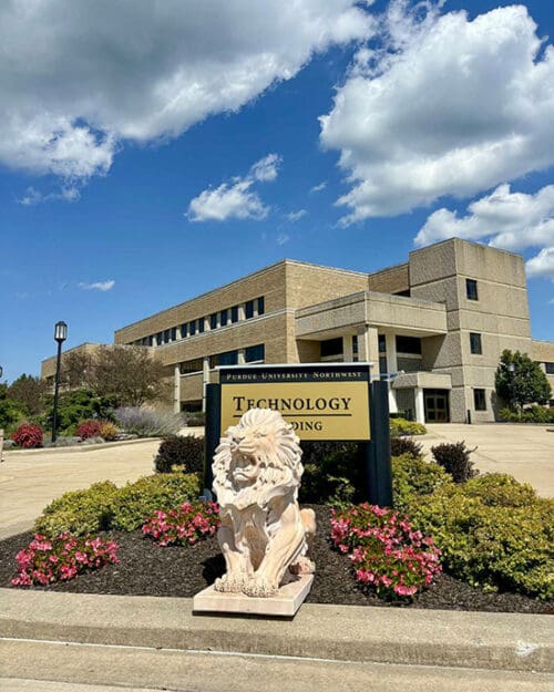 A lion statue on the PNW Westville Campus. The Technology Building sign is located behind the statue.