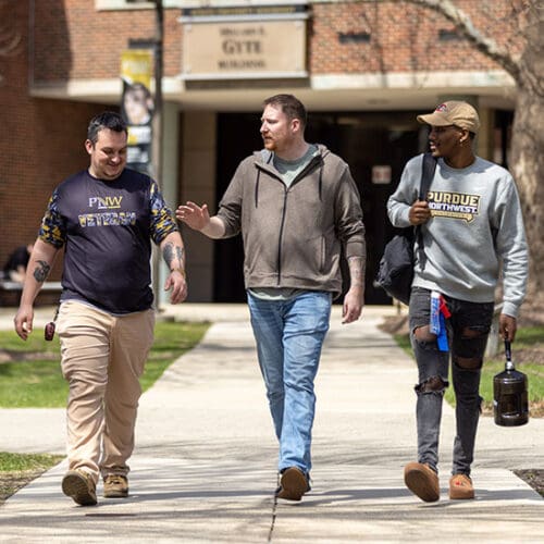 Three PNW students and staff members who are veterans walk through campus.