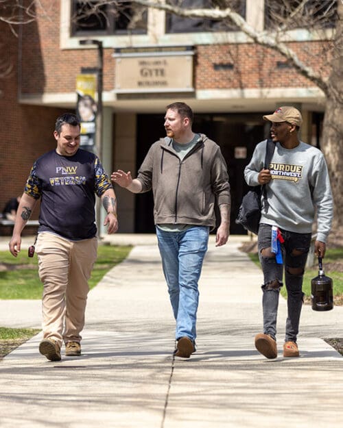 Three PNW students and staff members who are veterans walk through campus.