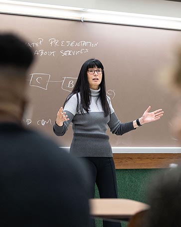 A PNW instructor speaks at the front of a classroom.