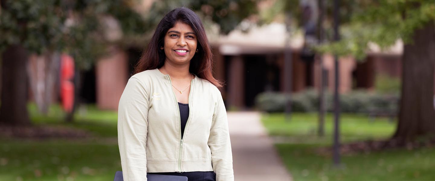 A PNW student stands outdoors on campus