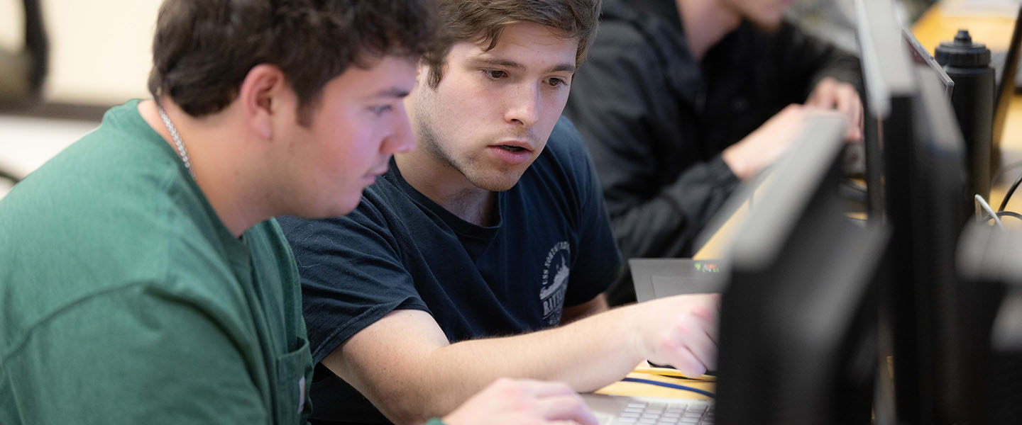 Two PNW students work at computers during a class.