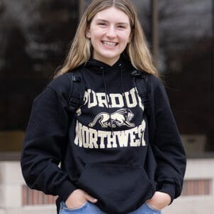 A PNW student in a Purdue Northwest hoodie stands outdoors.