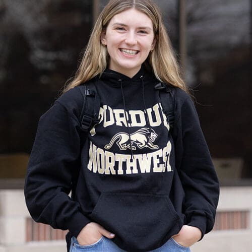 A PNW student in a Purdue Northwest hoodie stands outdoors.