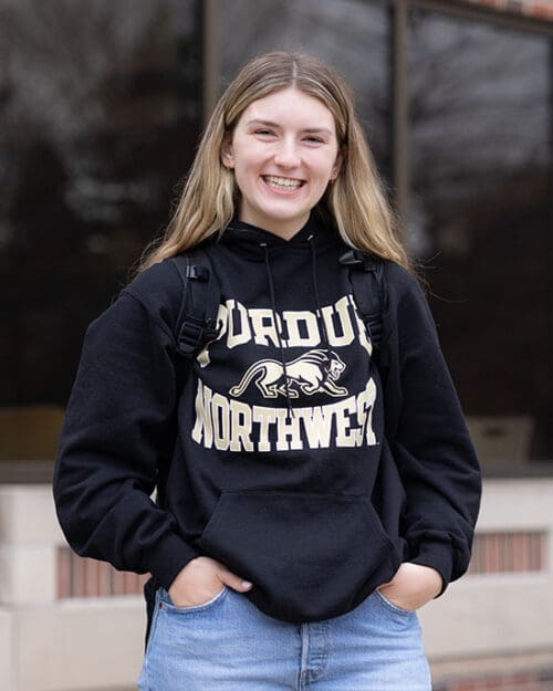 A PNW student in a Purdue Northwest hoodie stands outdoors.