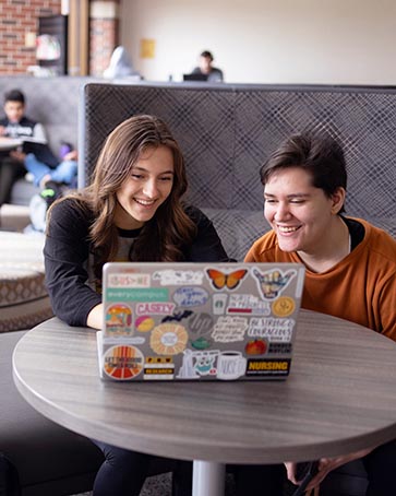 PNW students collaborate over a laptop.