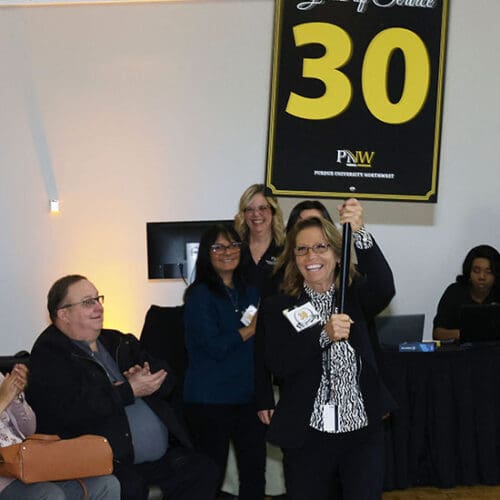 PNW employee Karen Sullivan carries a "30 years of Service" sign, leading a line of honorees.