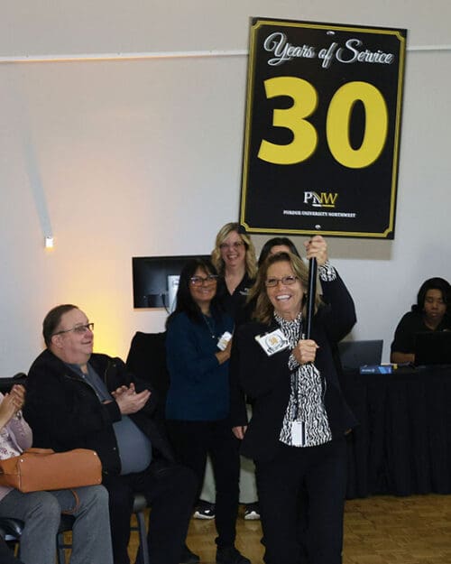 PNW employee Karen Sullivan carries a "30 years of Service" sign, leading a line of honorees.