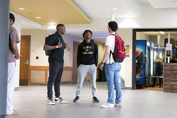 Three PNW students stand outside of Leo's Market in the Classroom Office Building.