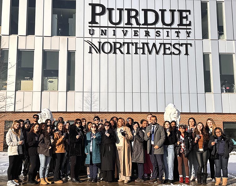 PNW students posing in front of the NILS building with their new passports in hand