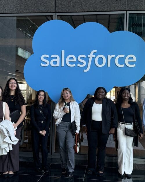 Diverse group of eight students in front of Salesforce sign