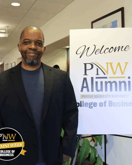 Person standing next to a Welcome PNW Alumni College of Business sign.