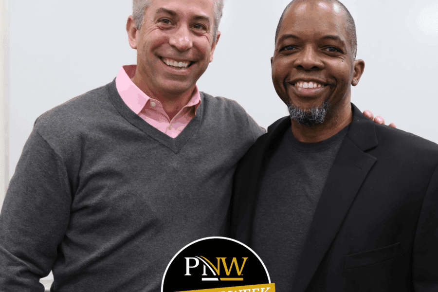 Well dressed men stand together smiling in front of a whiteboard