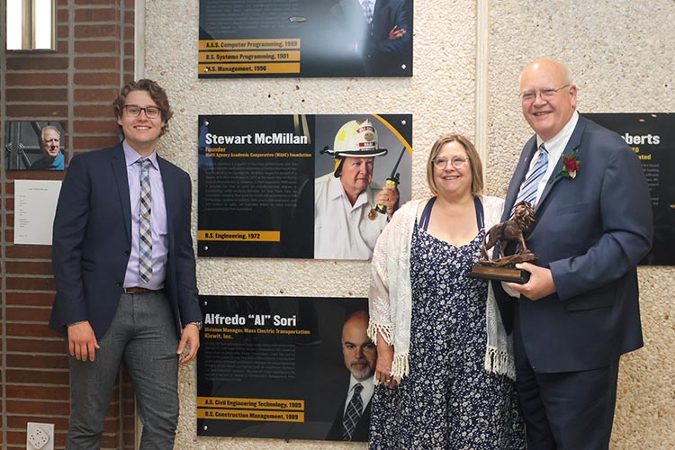 Stewart McMillan poses with his family in front of the plaque honoring him at the 2023 PNW Hall of Fame induction ceremony.