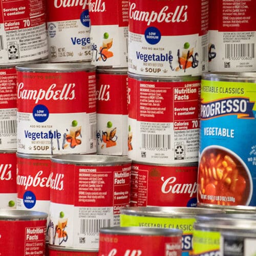 Campbell's and Progresso vegetable cans stacked on a shelf.