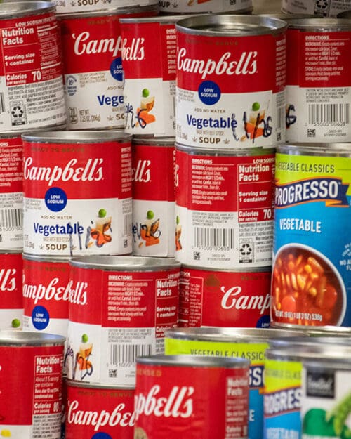 Campbell's and Progresso vegetable cans stacked on a shelf.