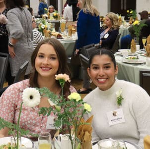 two students sit together during the women's leadership luncheon