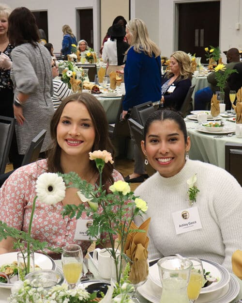 two students sit together during the women's leadership luncheon