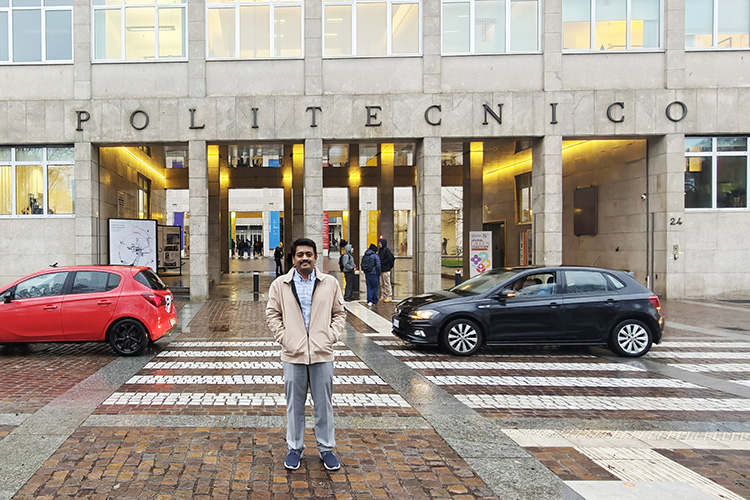 Magesh Chandramouli stands in front of an entry to Politecnico de Torino