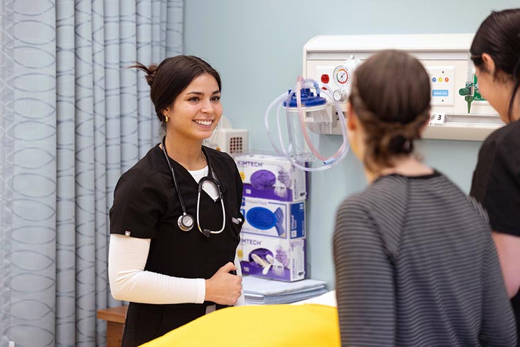 A PNW nursing student stands in a simulated exam room.