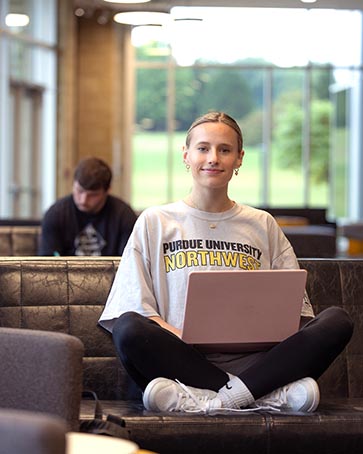 A PNW student sits in a campus lounge.