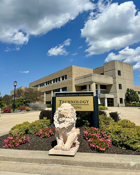 A white lion statue on PNW's Westville campus. The Technology Building and the sign for the Tech Building are pictured behind the lion.