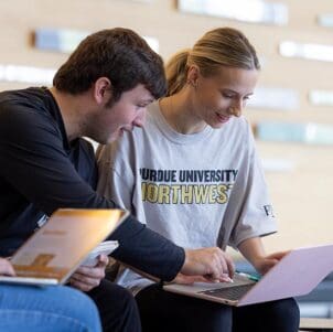 PNW students collaborate on a laptop.