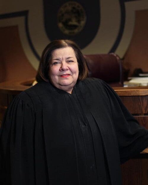 The Honorable Diane Kavadias Schneider poses in judicial robes in a courtroom