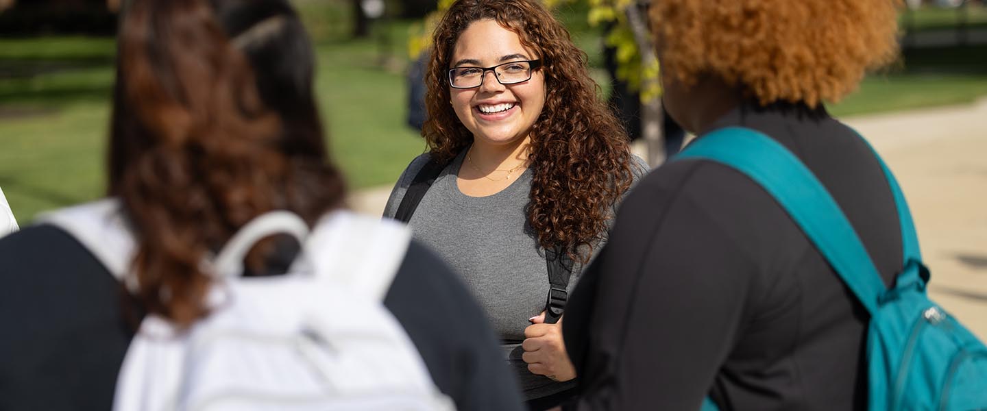 Three students talking outside on the PNW campus 1440x600