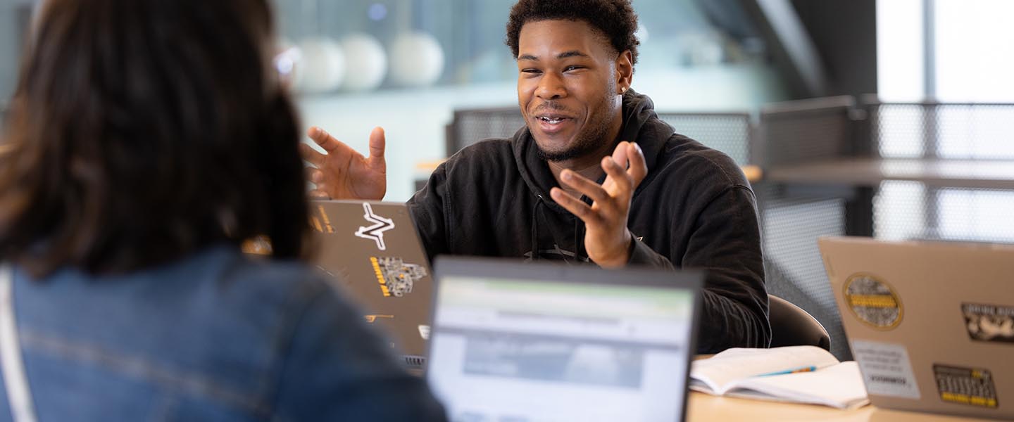 Two students talking with one another in the NILS building 1440x600