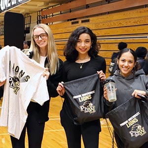 PNW athletes hold PNW Lions gear in the Fitness and Recreation Center.