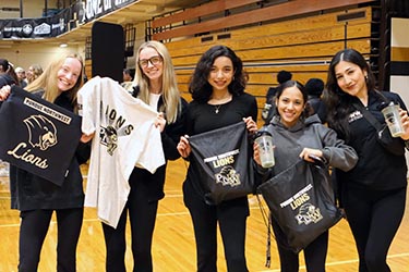 PNW athletes hold PNW Lions gear in the Fitness and Recreation Center.