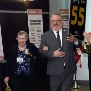 PNW Chancellor Chris Holford escorts 55 years of service honoree Shelia Rezak through the crowd.