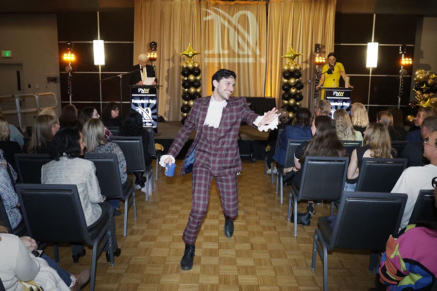A man in ruffles and a checkered suit runs through a crowd
