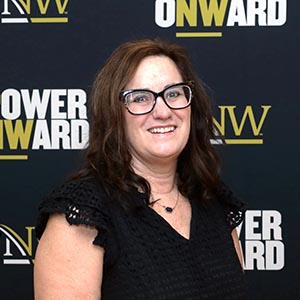 Amy Bugg before a PNW/Power Onward banner.